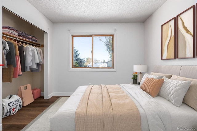 bedroom with a textured ceiling, dark wood-type flooring, and a closet