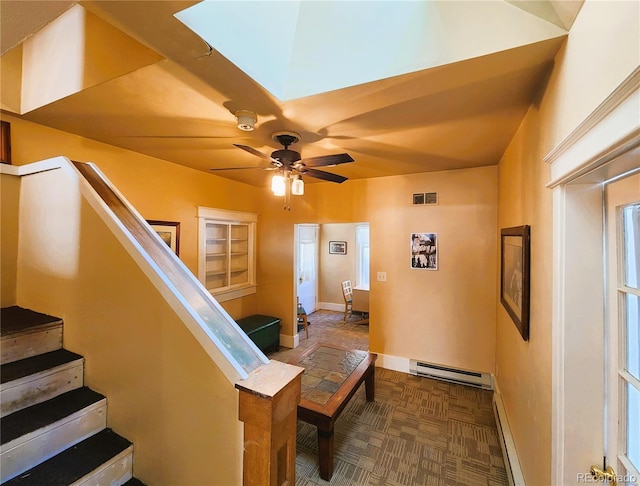 staircase with visible vents, a baseboard heating unit, ceiling fan, baseboards, and baseboard heating