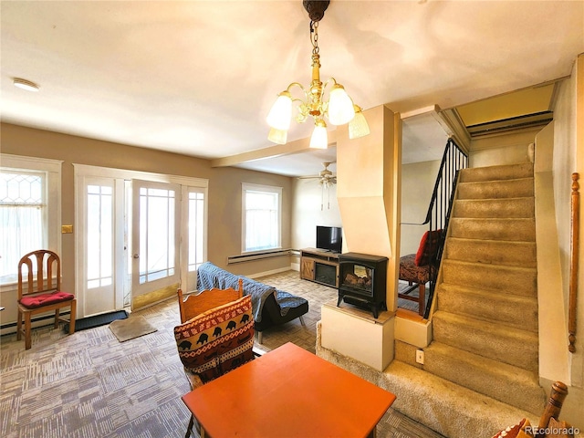 living room with a baseboard heating unit, stairway, carpet floors, a wood stove, and a notable chandelier