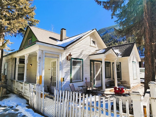 view of front of home featuring a porch, a chimney, and fence