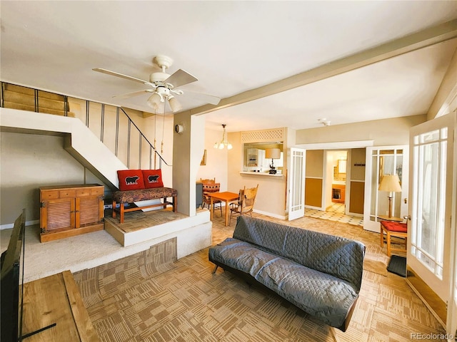 living room featuring beamed ceiling, stairway, ceiling fan with notable chandelier, and baseboards