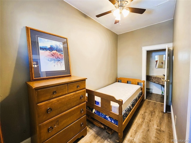 bedroom featuring a ceiling fan, a baseboard heating unit, baseboards, and wood finished floors