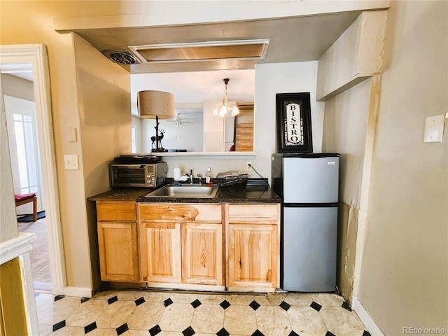 kitchen with dark countertops, visible vents, freestanding refrigerator, and a sink