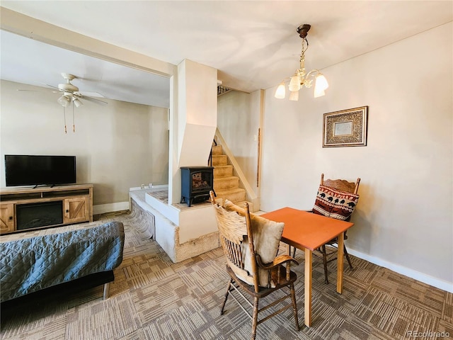 dining room with ceiling fan with notable chandelier, stairs, and baseboards