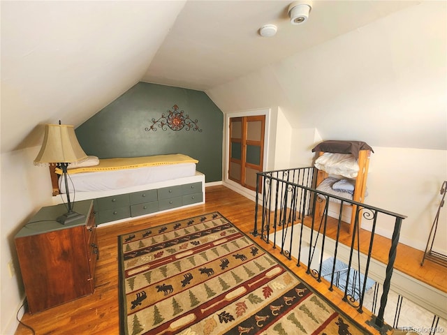 bedroom featuring baseboards, wood finished floors, and vaulted ceiling