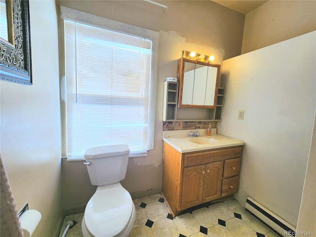 bathroom featuring baseboards, baseboard heating, vanity, and toilet