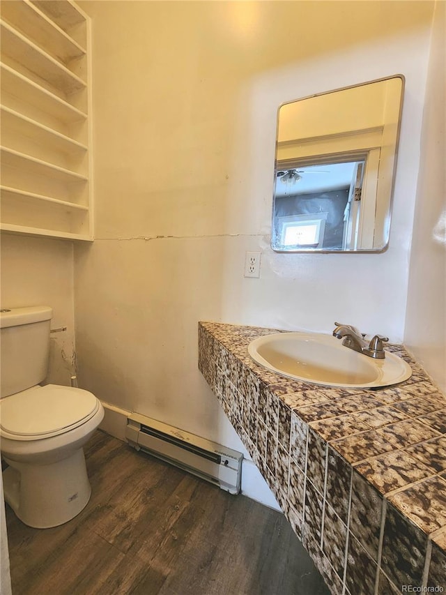 bathroom featuring a sink, a baseboard radiator, toilet, and wood finished floors