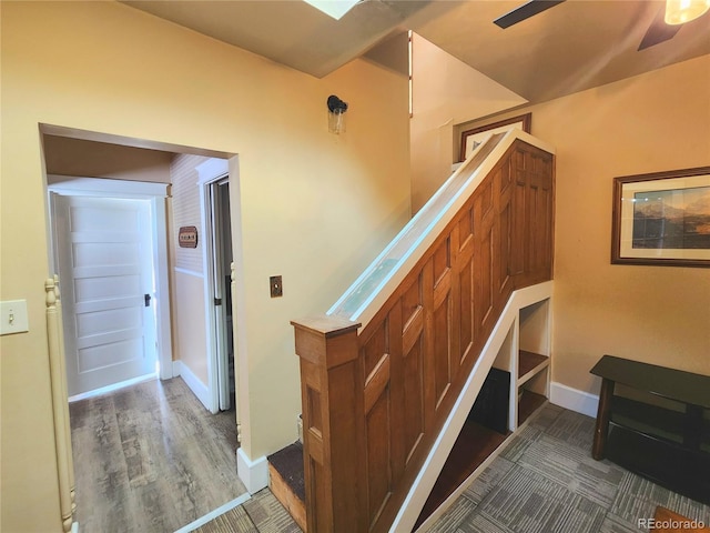 stairs with a ceiling fan and baseboards