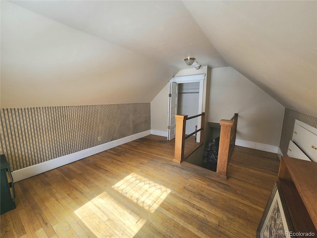 bonus room featuring baseboards, lofted ceiling, hardwood / wood-style floors, and wallpapered walls