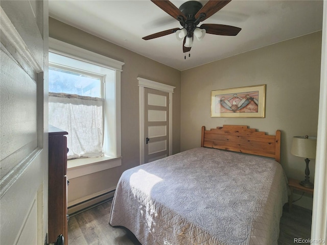 bedroom with a baseboard heating unit, wood finished floors, and a ceiling fan