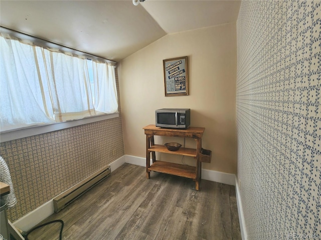 interior space featuring vaulted ceiling, wood finished floors, baseboards, and baseboard heating