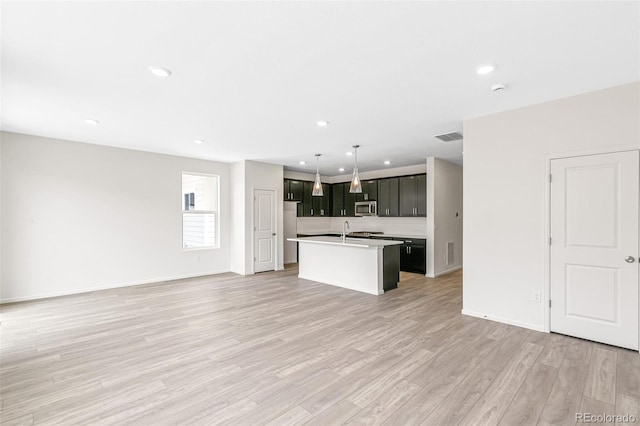 13342 E 110th Way, Commerce City, CO 80022 - kitchen with open floor plan, appliances with stainless steel finishes, an island with sink, light countertops, and light wood-style floors
