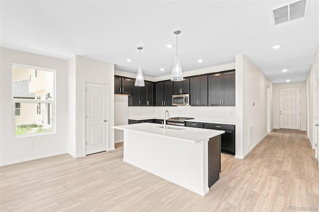 13342 E 110th Way, Commerce City, CO 80022 - kitchen featuring stainless steel appliances, a sink, light wood finished floors, light countertops, and a kitchen island with sink