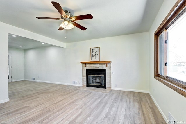 unfurnished living room with visible vents, ceiling fan, baseboards, light wood-type flooring, and a fireplace