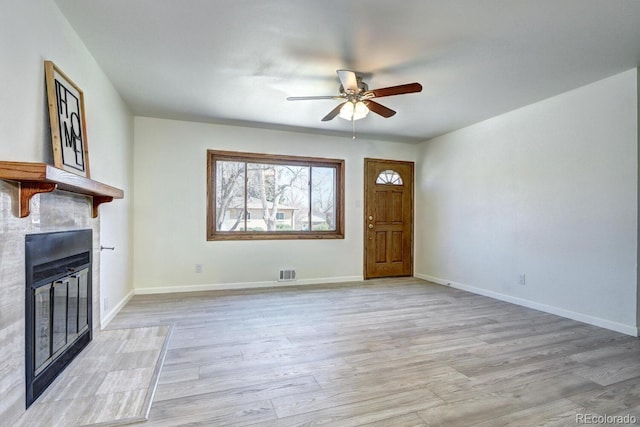 unfurnished living room featuring a ceiling fan, visible vents, baseboards, a glass covered fireplace, and light wood-type flooring