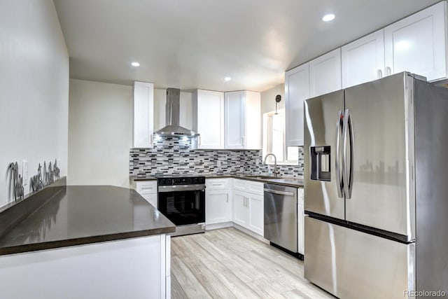 kitchen featuring stainless steel appliances, dark countertops, wall chimney exhaust hood, and decorative backsplash