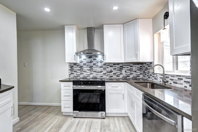 kitchen with a sink, black electric range, stainless steel dishwasher, dark countertops, and wall chimney range hood