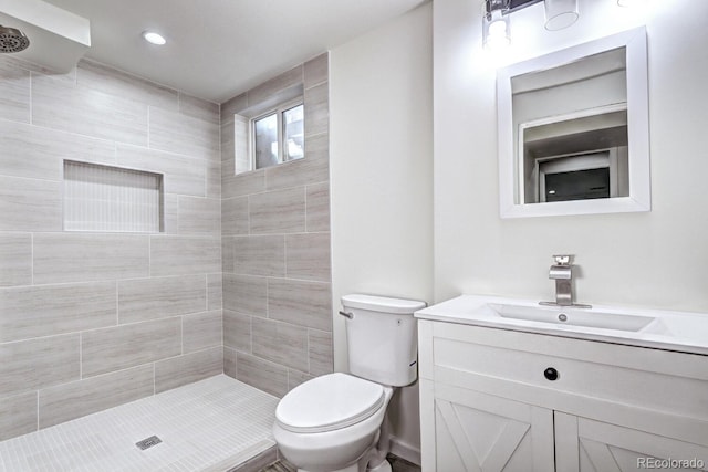 bathroom featuring tiled shower, recessed lighting, toilet, and vanity