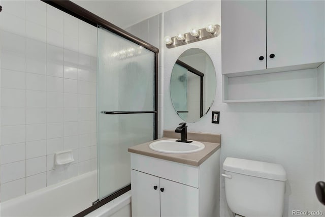 full bathroom with vanity, bath / shower combo with glass door, and toilet