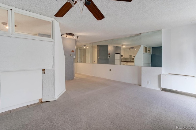 empty room with carpet flooring, ceiling fan, and a textured ceiling