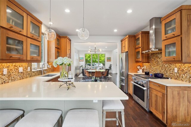 1511 S Pennsylvania St, Denver, CO 80210 - kitchen featuring appliances with stainless steel finishes, wall chimney exhaust hood, a sink, brown cabinetry, and recessed lighting