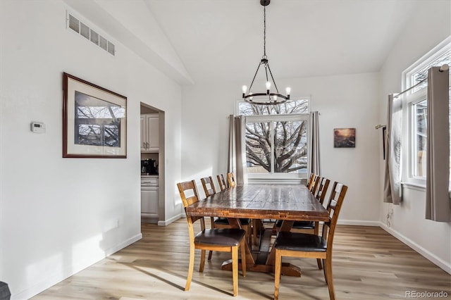 dining area featuring light wood-type flooring, visible vents, lofted ceiling, and baseboards