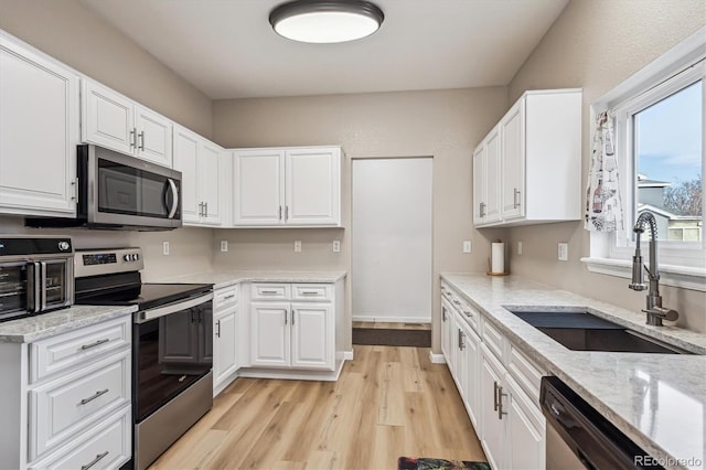 kitchen featuring a sink, white cabinets, light wood-style flooring, and stainless steel appliances