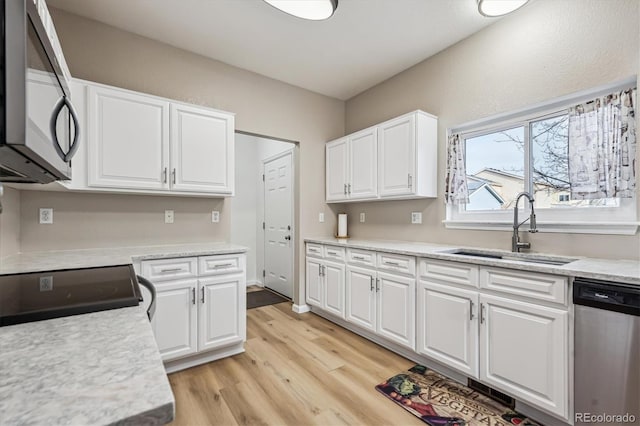 kitchen featuring a sink, stainless steel appliances, light wood-style floors, and white cabinetry