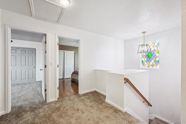 corridor with an upstairs landing, carpet flooring, attic access, and baseboards