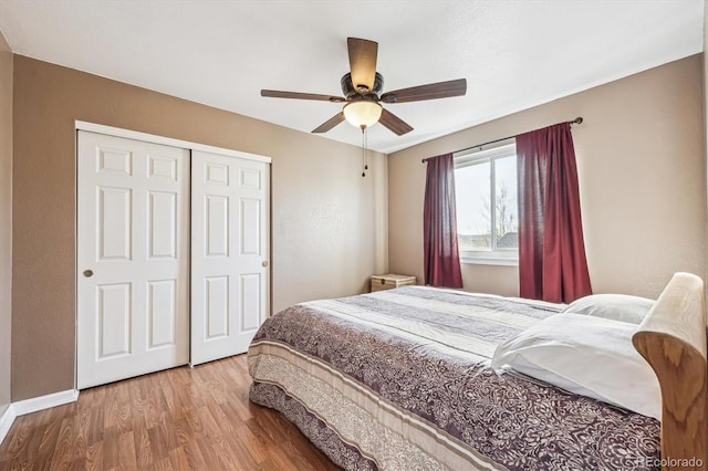 bedroom with a closet, a ceiling fan, baseboards, and wood finished floors