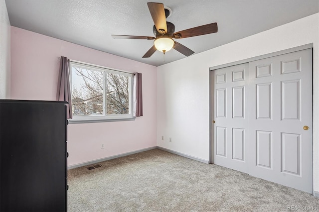 unfurnished bedroom with carpet, visible vents, baseboards, a closet, and a textured ceiling