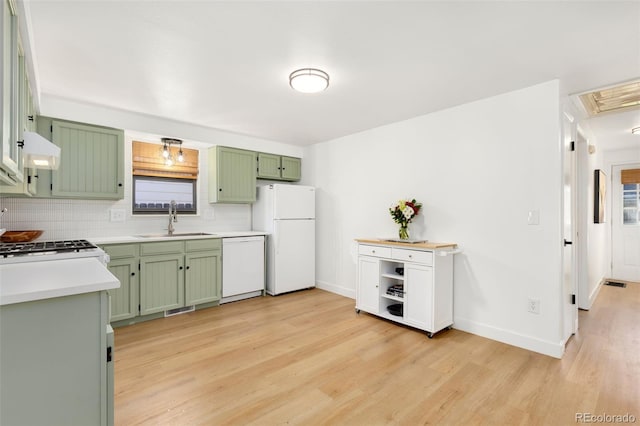 kitchen with sink, green cabinetry, backsplash, white appliances, and exhaust hood