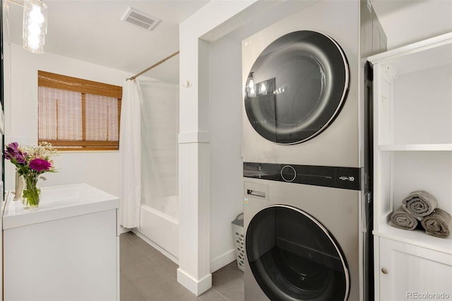 laundry room with stacked washer and clothes dryer and light tile patterned floors