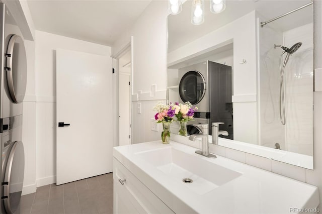 bathroom with tile patterned floors, stacked washer / drying machine, a shower, and vanity