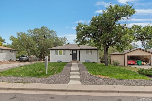 view of front facade with a front yard, a detached garage, an outbuilding, and fence