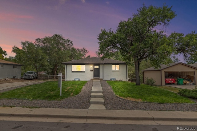 view of front of house featuring a lawn, an outbuilding, a carport, and a garage