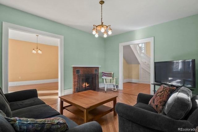 living room with a fireplace, hardwood / wood-style flooring, and an inviting chandelier