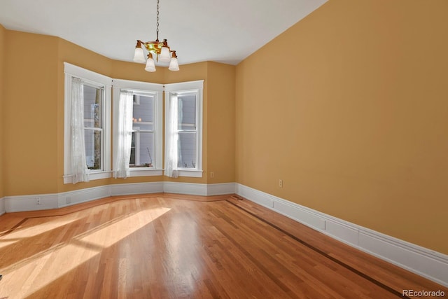 unfurnished room with an inviting chandelier and wood-type flooring