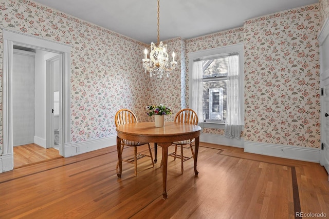 dining area with light hardwood / wood-style floors and an inviting chandelier