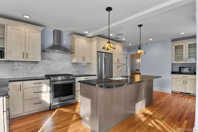 kitchen with appliances with stainless steel finishes, wall chimney exhaust hood, light hardwood / wood-style flooring, and hanging light fixtures