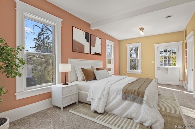 bedroom featuring beam ceiling and light colored carpet