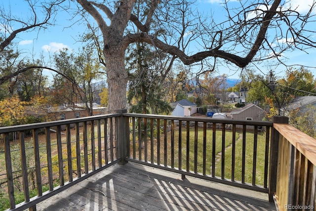 wooden deck featuring a storage unit and a lawn