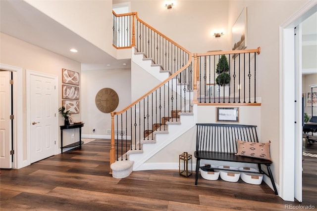 stairs with hardwood / wood-style flooring and a high ceiling