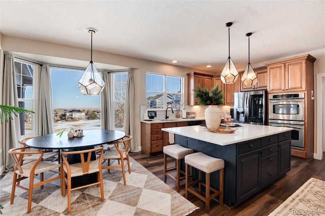 kitchen featuring a kitchen island, pendant lighting, decorative backsplash, stainless steel appliances, and dark wood-type flooring