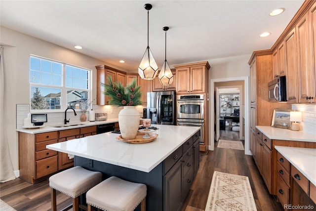 kitchen with sink, hanging light fixtures, stainless steel appliances, dark hardwood / wood-style floors, and a kitchen island