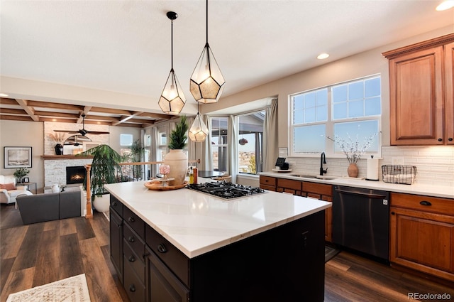 kitchen with a fireplace, stainless steel gas stovetop, dishwasher, sink, and a center island