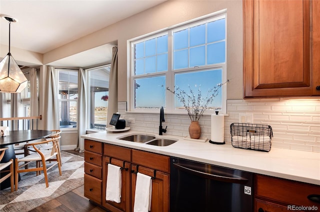 kitchen featuring dark hardwood / wood-style floors, pendant lighting, sink, black dishwasher, and decorative backsplash