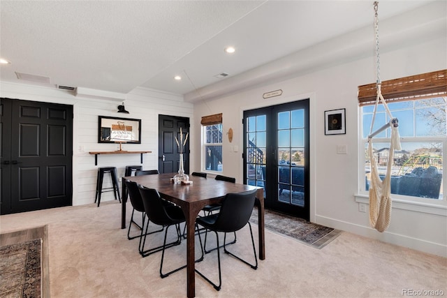 dining space featuring light colored carpet, french doors, and a textured ceiling