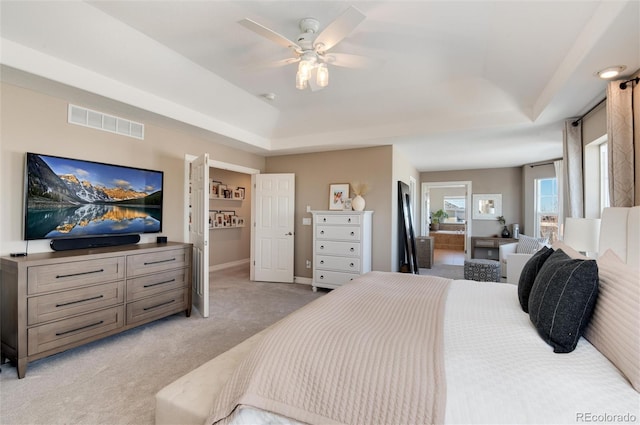 carpeted bedroom with a raised ceiling and ceiling fan