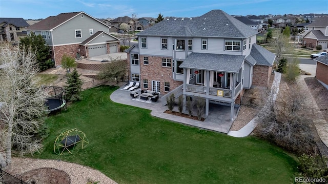 back of house featuring a residential view, roof with shingles, a wooden deck, a lawn, and a patio